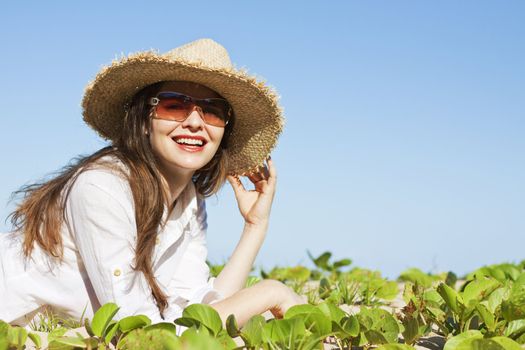 A beautiful woman lying smiling on the beach wearing hat and sunglasses 