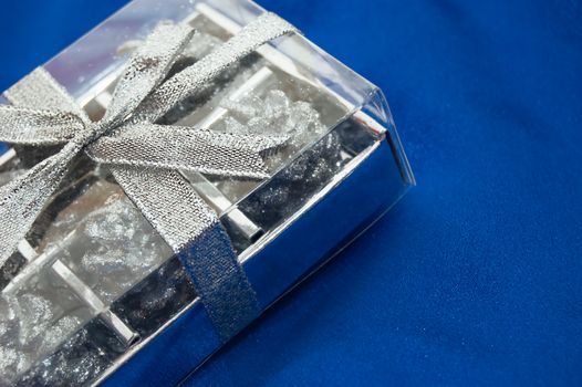 silver gift box on blue satin fabric