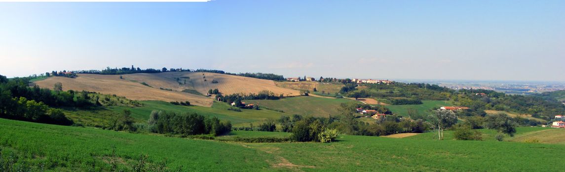 Two photos of hills, with green grass and blue sky, photomerged