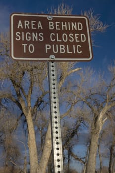 area behind signs closed to public - metal brown sign with cottonwood trees in background