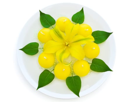 floral spa decoration with lily, candles and green leaves over white background