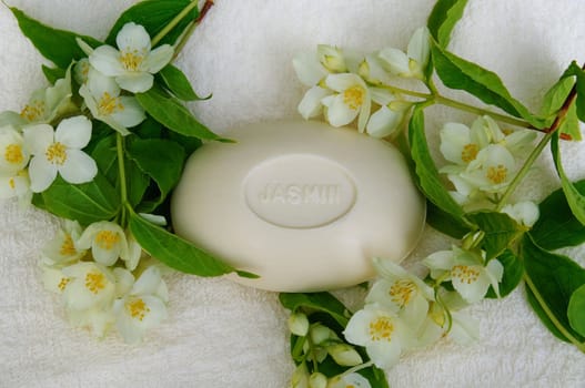 A piece of jasmine soap surrounded by jasmine flowers