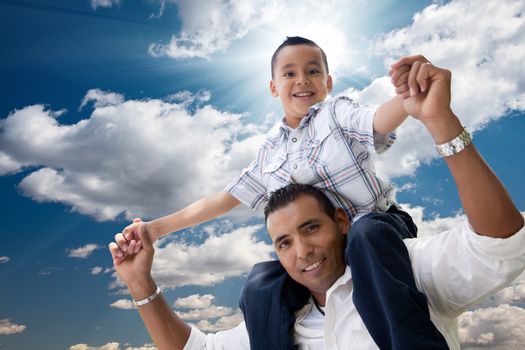 Hispanic Father and Son Having Fun Over Clouds and Blue Sky with Sun Rays.