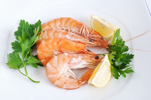 three raw prawns with lemon and parsley on a white plate isolated with clipping path