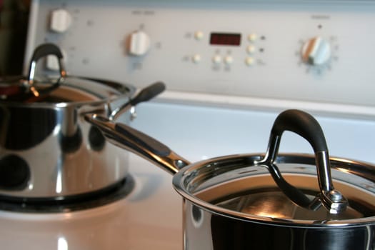 Two stainless steel pots sitting on an oven.