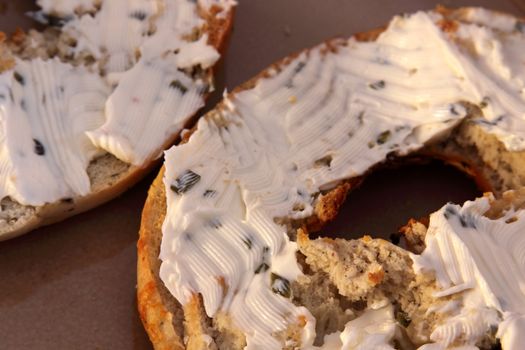 A toasted bagel with cream cheese with herbs.
