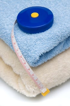 Pile of towels and tape measure, white background