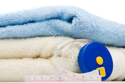 Pile of towels and tape measure, white background