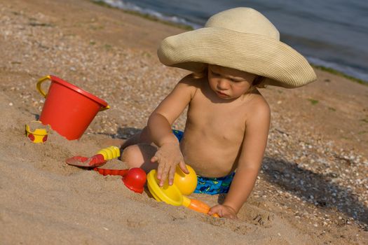little girl in the bonnet plaing with sand,
