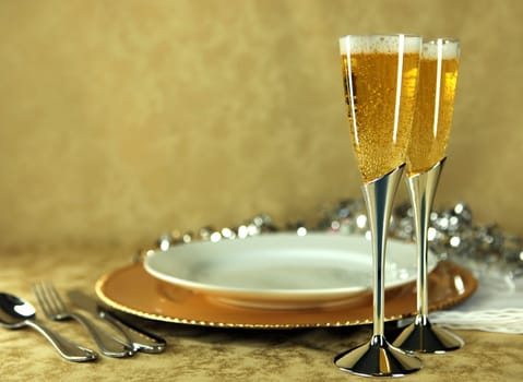 Pair of Champagne Flutes Next to Dinner Place Setting With Copy Space