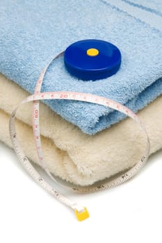 Pile of towels and tape measure, white background