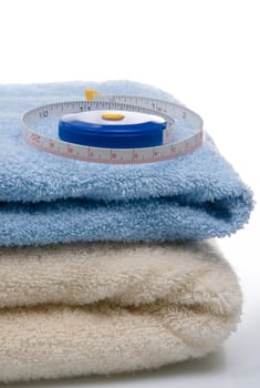 Pile of towels and tape measure, white background