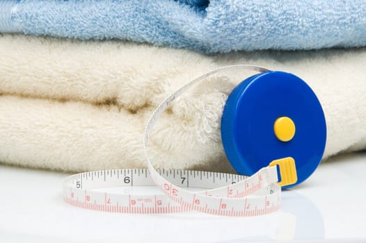 Pile of towels and tape measure, white background