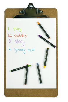 A clipboard holding paper with a childs to-do list written with colorful crayons