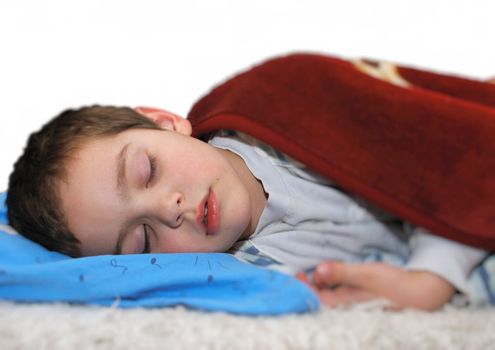 a boy is sleeping on a bed covered with a blanket