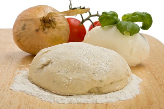 yeast dough, cheese, tomatoes and an onion on a wooden board