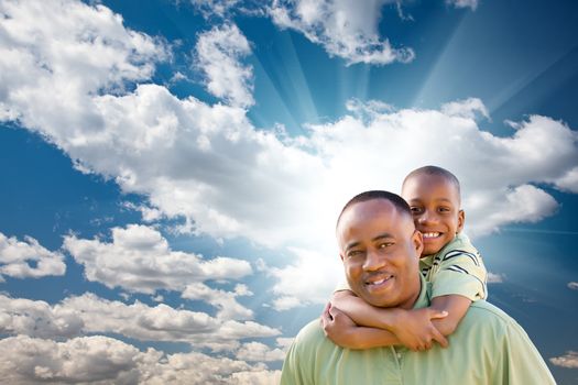 Happy African American Man with Child Over Blue Sky, Clouds and Sun Rays.