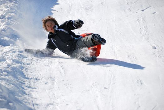 boy falling while sledding fast down the hill with snow background