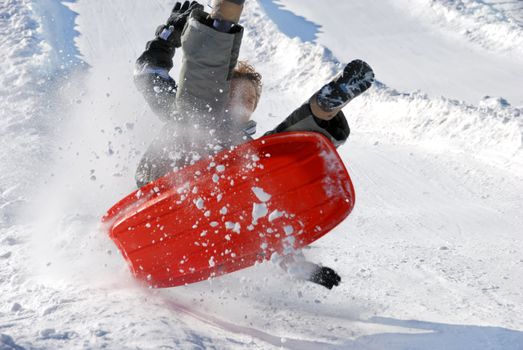 boy in the air while sledding fast down the hill with snow background