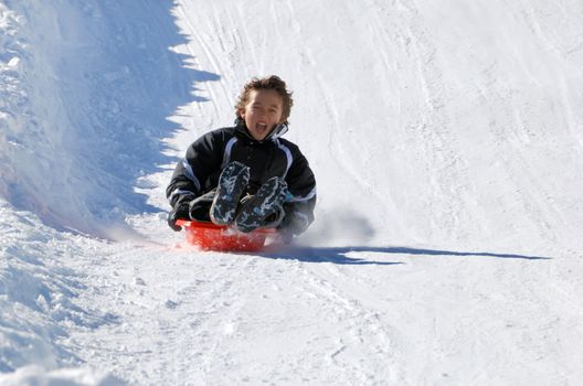 boy sledding fast down the hill with snow background