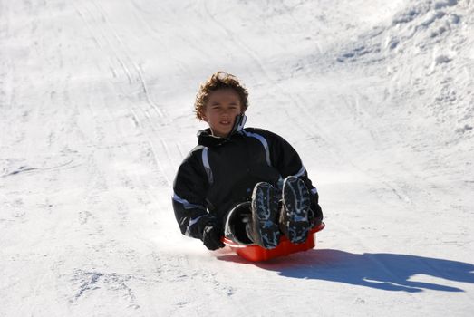 boy sledding fast down the hill with snow background