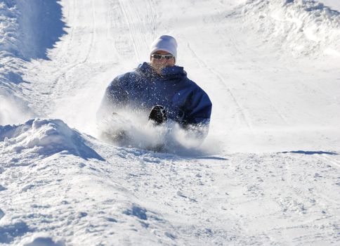 man braking while sledding fast down the hill with snow background