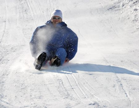 man sledding fast down the hill with snow background