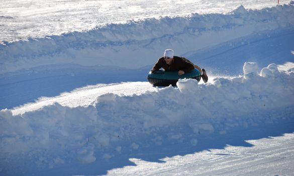 man tubing fast down the hill with snow background