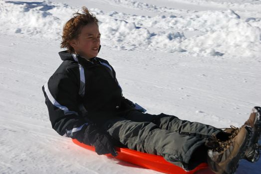 scared boy sledding fast down the hill with snow background