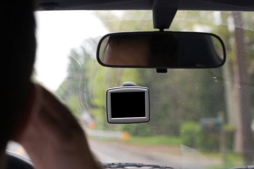 Driver talking on his cell phone while using a portable gps unit that is mounted to the windshield. The blank screen includes clipping path for easy isolation.
