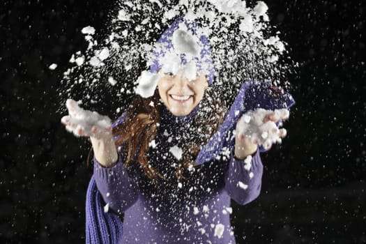 Snow from woman's hands in the night