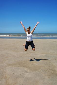 Blond teenage girl jumping on the beach.
