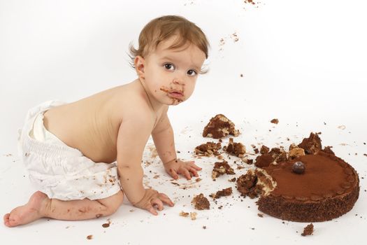 An adorable one year old girl enjoying her first birthday cake.
