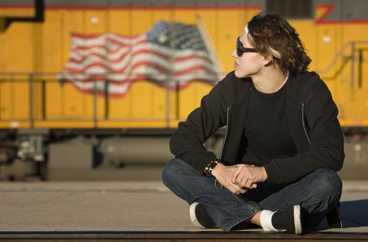 Teenage boy wearing glasses in front of train
