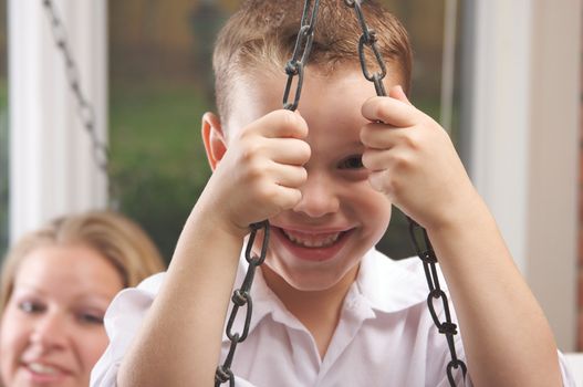 Young Boy Smiles for The Camera as His Mom Looks On