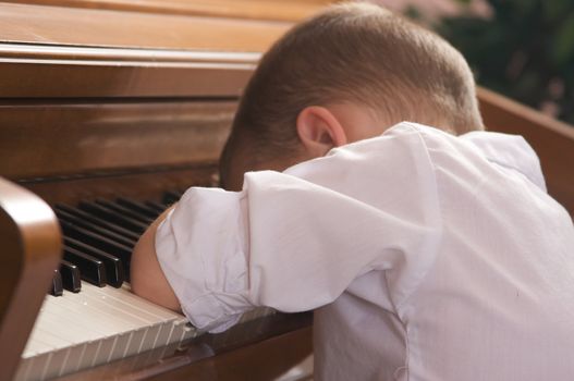 Sad Young Boy with Head on the Piano
