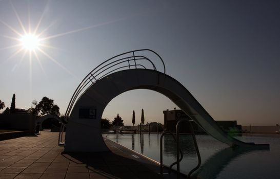 Bath pool with white slide during a sunset