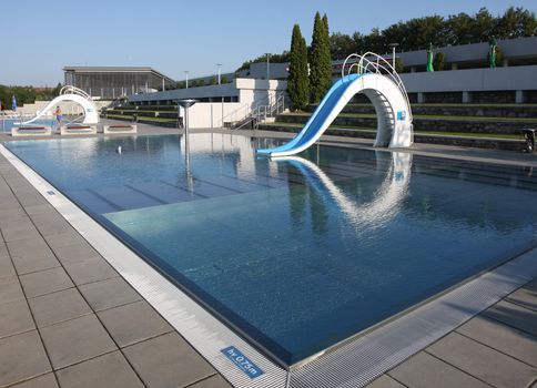 Dispeopled bath pool with white slide