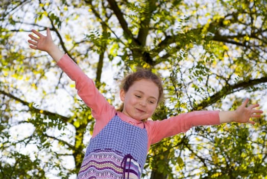 girl at playground, balancing on beam, looking at up, trees/sky behind