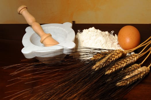 Flour, corn stalks, egg and mortar on wood table