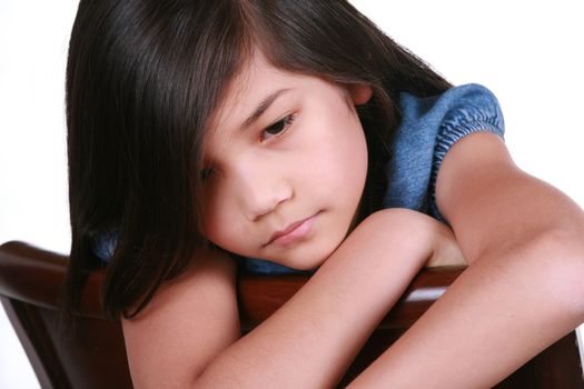 Sad nine year old girl sitting on chair, bored.