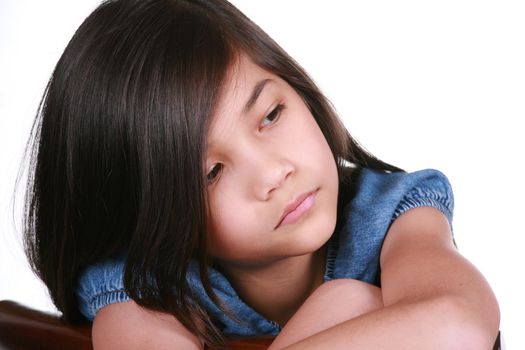 Sad nine year old girl sitting on chair, bored.