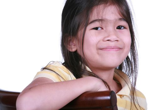 Beautiful little girl sitting on chair smiling, part Asian - Scandinavian descent