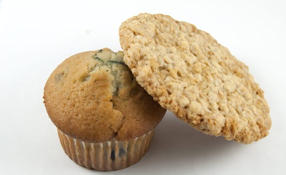 An oatmeal cookie next to a blueberry muffin.