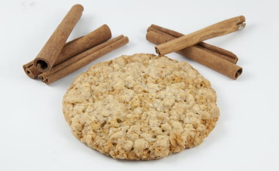 A oatmeal cookie next to cinnamon.