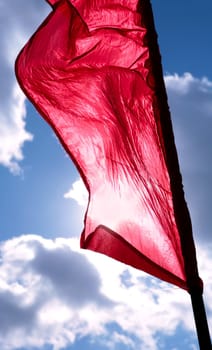 flapping red banner on background cool blue sky with clouds
