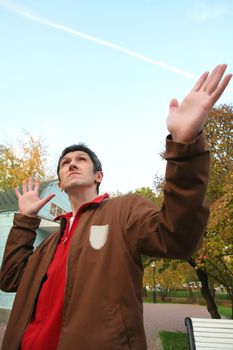 Man, Peers into Sky with Raised Hand