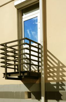 metallic balcony, his shade on yellow wall and blanching door with reflection blue sky
