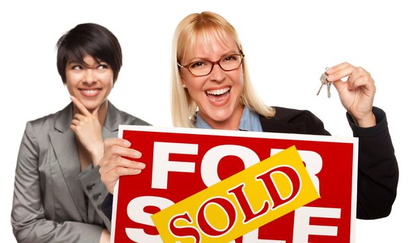 Hispanic Female Behind with Attractive Blonde in Front Holding Keys and Sold For Sale Sign Isolated on a White Background.