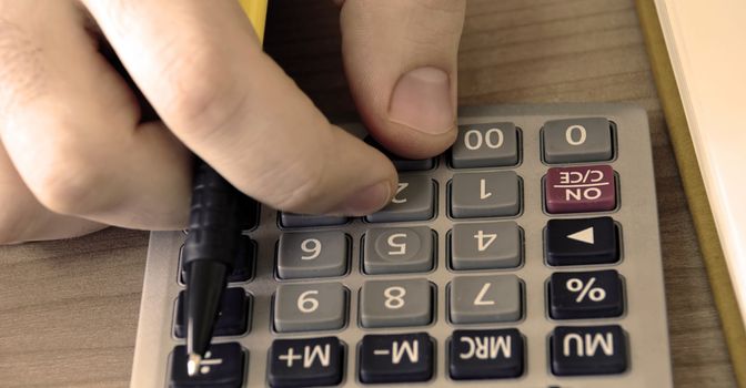 man fingers over gray calculator buttons closeup